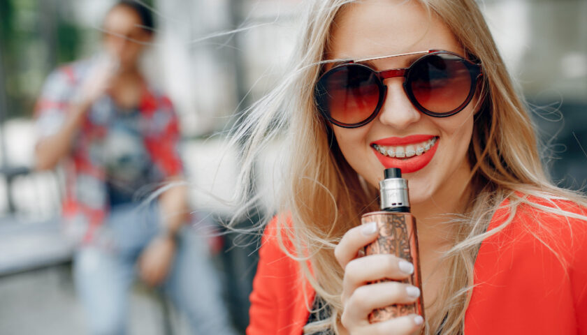 une femme souriante avec une vapoteuse